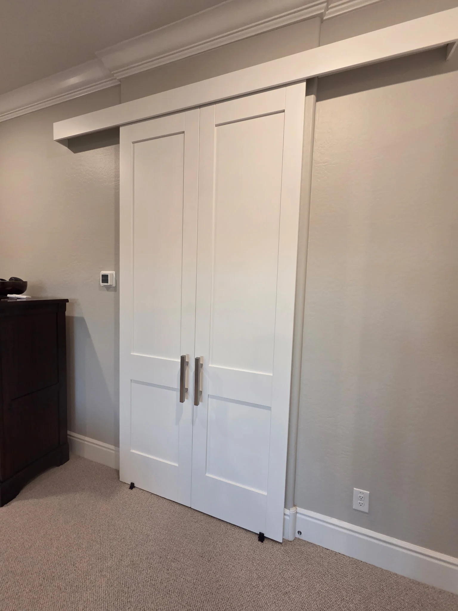 Two Panel Double Slider barn doors, white Shaker-style leaves with tall upper and shorter lower solid panels, center pulls and a concealed track, shown closed